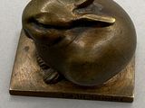 une sculpture en bronze représentant un lapin assis sur un bloc