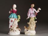 pair of porcelain figurines of a woman and a man with a dog