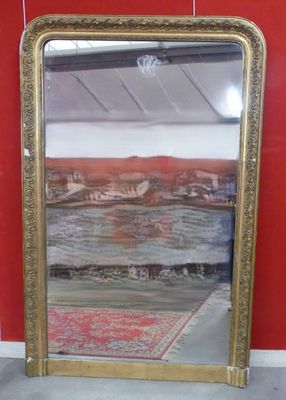 un miroir posé par terre près d'un mur rouge
