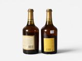two bottles of wine sitting next to each other on a white surface