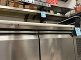 stainless steel counter top in a commercial kitchen with lots of food on shelves