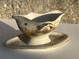 une saucière ornée d'un oiseau, posée sur une soucoupe