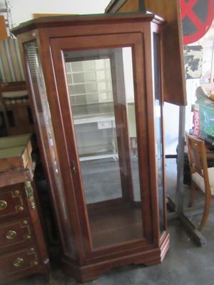 a tall wooden cabinet with a glass door in a room