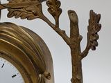 a gold clock with a bird on top of it