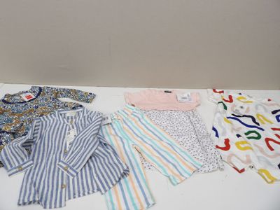 de nombreux vêtements de bébé disposés sur une table blanche