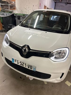 l'avant d'une voiture blanche garée dans un garage, à côté d'une poubelle