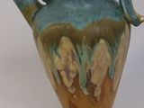 a blue and green vase with a handle on a white surface