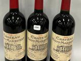 three bottles of red wine are lined up on a white surface