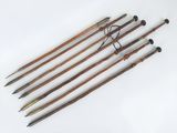 four old wooden canes are lined up on a white surface