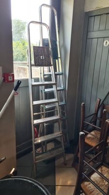 a ladder that is leaning against a wall next to a chair