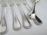 five forks and a spoon on a white table