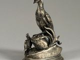 a silver figurine of a bird sitting on top of a bowl