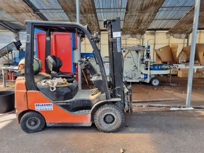 un chariot élévateur garé dans un entrepôt dont la porte est rouge