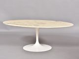 une table ovale en marbre avec un piètement blanc sur fond gris