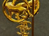 a close up of a gold and pearl brooch with a bird on it