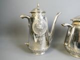 two silver teapots sitting next to each other on a table