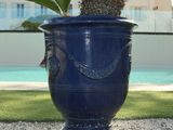 a large blue vase with a palm tree in it