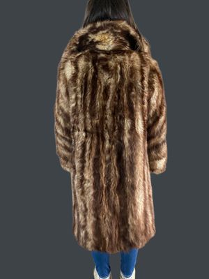 a woman in a brown fur coat standing on a gray background