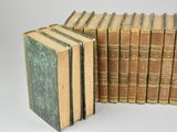 several old books stacked on top of each other on a white surface