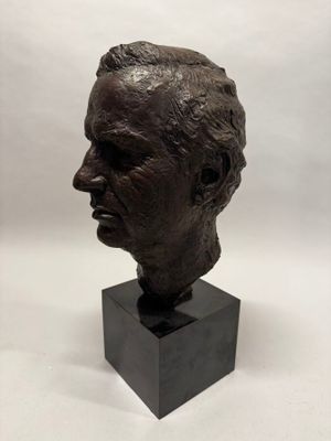 un buste en bronze représentant la tête d'un homme, posé sur un socle noir