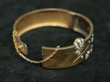 gold bracelet with pearls and chains on a black background