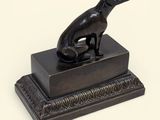 statue d'un chien assis sur une boîte posée sur une surface blanche