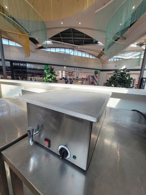 un plan de travail en acier inoxydable équipé d'une plaque de cuisson, situé dans un immeuble