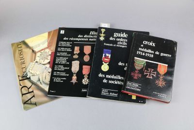 trois livres posés sur une table, sur lesquels sont posées des médailles