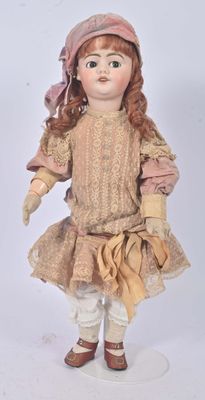 an old fashioned doll with red hair and a pink hat on a white surface