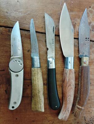 cinq types de couteaux différents posés sur une table en bois