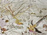 deux oiseaux qui volent dans les airs près de quelques fleurs