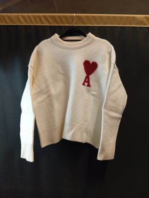 un pull blanc orné d'un cœur rouge, suspendu à un cintre