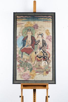 une image représentant un tableau posé sur un chevalet, sur lequel figurent un homme et une femme