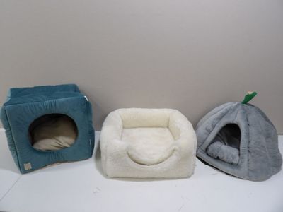 three dog beds and a cat bed on a shelf