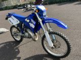a blue and white dirt bike parked in a parking lot