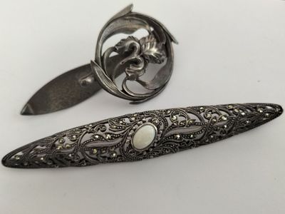 two antique silverware items on a white surface with a white background