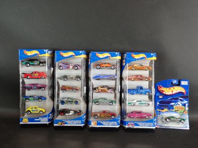 Six petites voitures Hot Wheels sont alignées en rang sur une table
