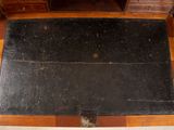 a black tile on the floor next to a wooden desk