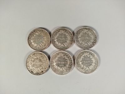 six different british coins sitting on top of a white surface