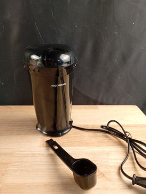 un moulin à café et une cuillère doseuse posés sur une table