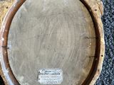 une vieille plaque en laiton encadrée de bois, posée sur un sol recouvert de moquette