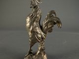 a silver statue of a rooster on a gray surface
