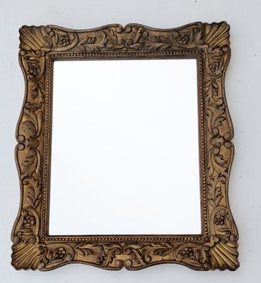 an ornate gold framed mirror on a white wall with a white background