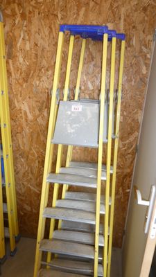 yellow ladders are lined up against a wall in a room