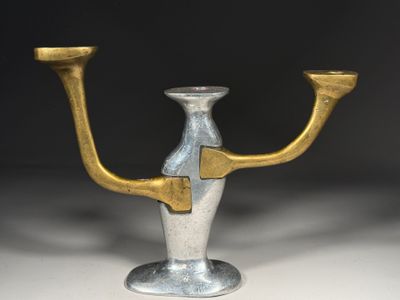 un bougeoir en argent et en or posé sur une table blanche