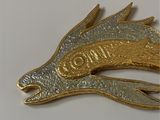 a gold and silver dragon brooch on a white surface