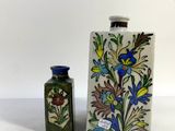 two vases with flowers and a bird on them sitting next to each other