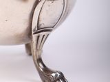 a silver bowl with a bird on it on a white surface
