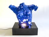 a blue sculpture on a black stand with a light on it