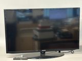 a flat screen tv sitting on a table next to a remote control